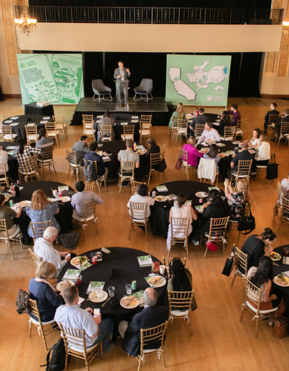 overhead view of man addressing group of people sitting at round tables in an event hall