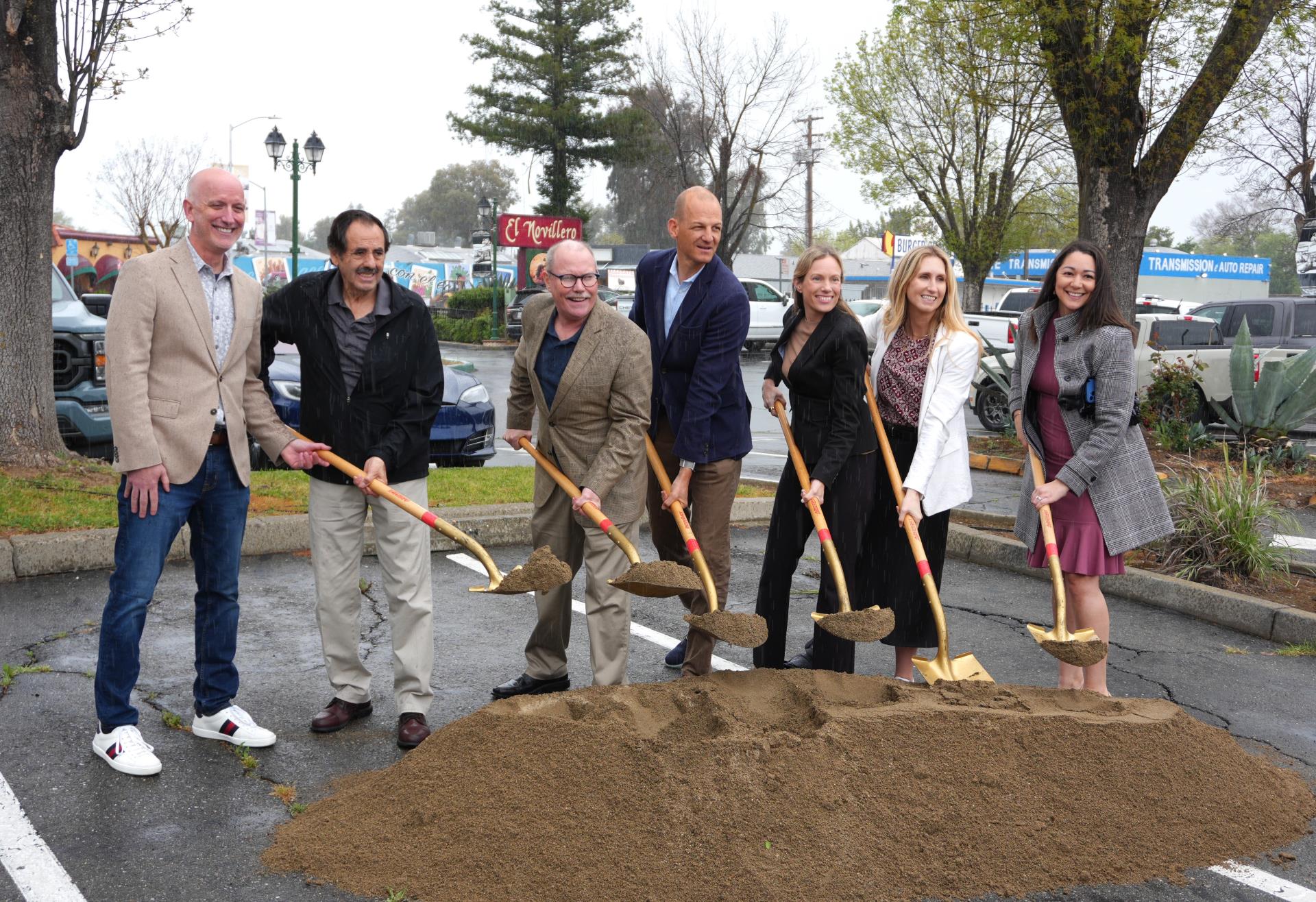 image of seven people smiling with shovels in dirt