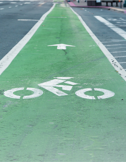 pavement marker of illustration of person riding a bike in a green striped bike lane in the street