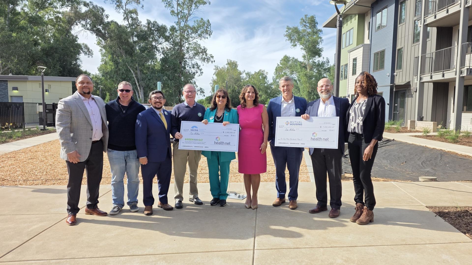 Leaders from each organization standing for photo with two giant checks