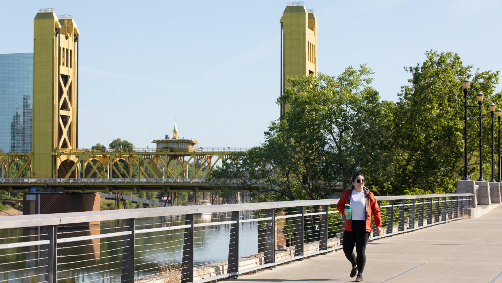 Woman walking on city of Sacramento waterfront with J Street bridge in background