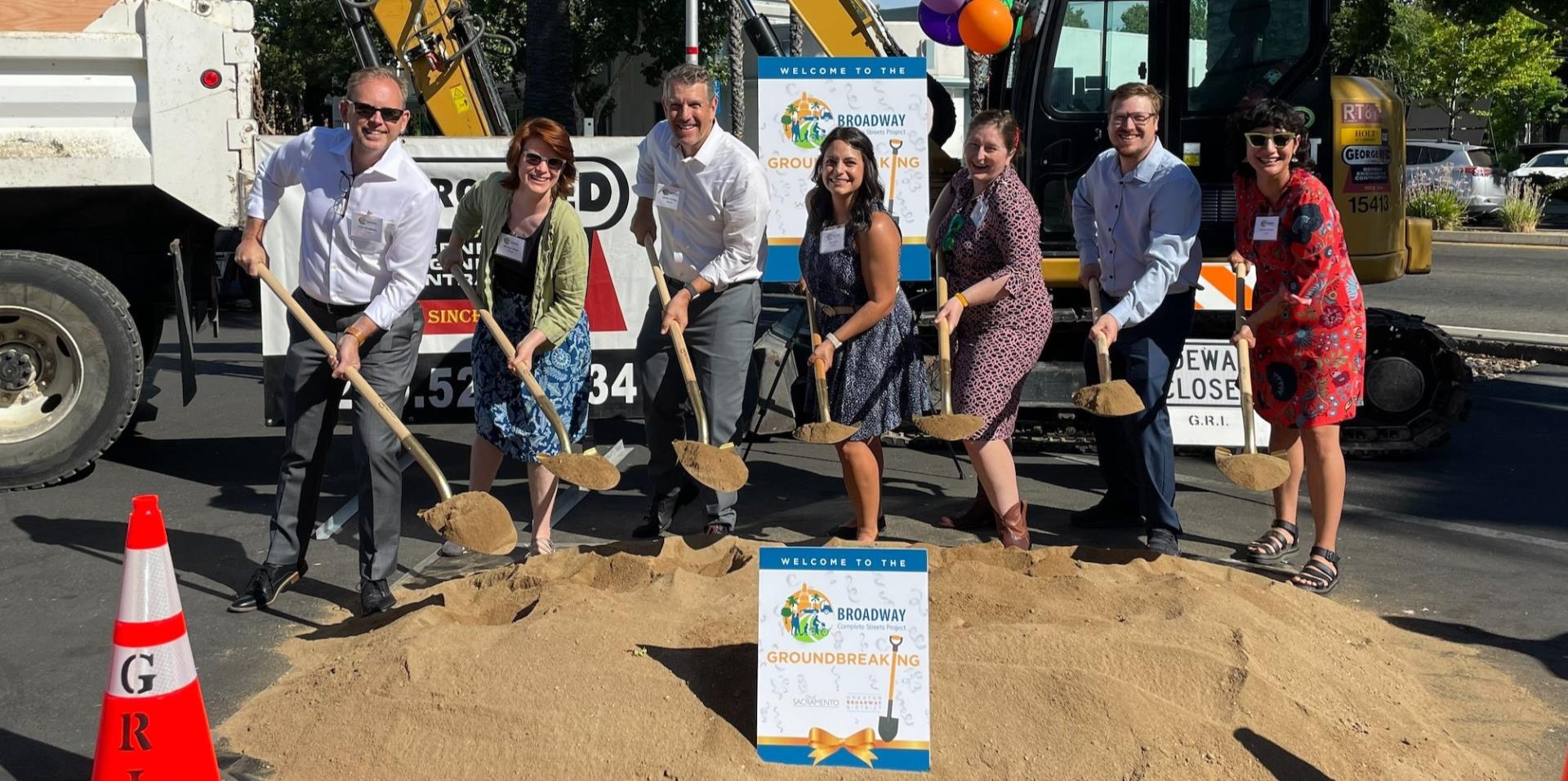Group of people posing for photo with shovels of dirt